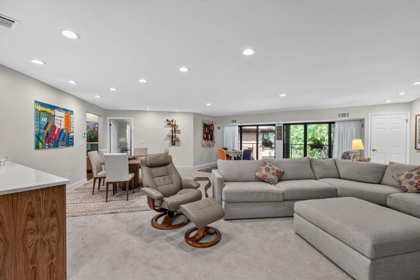 Bright living room with a grey sectional, swivel chairs, and large sliding glass doors to the patio.